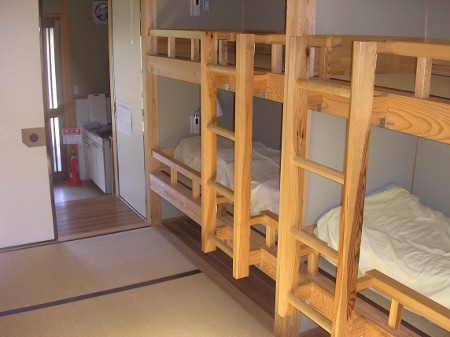 畳の部屋の右側に木の梯子がついた二段ベッドが2つある宿泊部屋内の写真