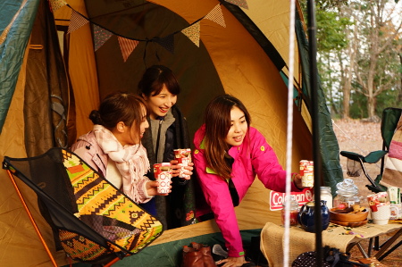 テントの入口付近で3人の女性が飲み物を持っている写真