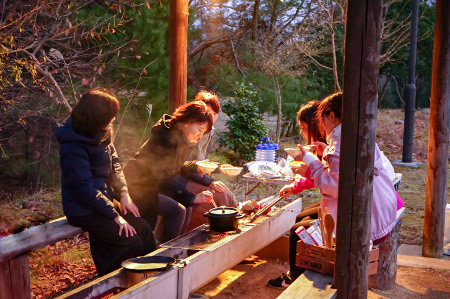 5名の女性のグループが、あづまやでバーベキューコンロでバーベキューを焼き、鍋を置いて調理して食べている写真