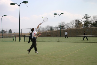 オムニテニスコートでテニスを楽しんでいる人達の写真