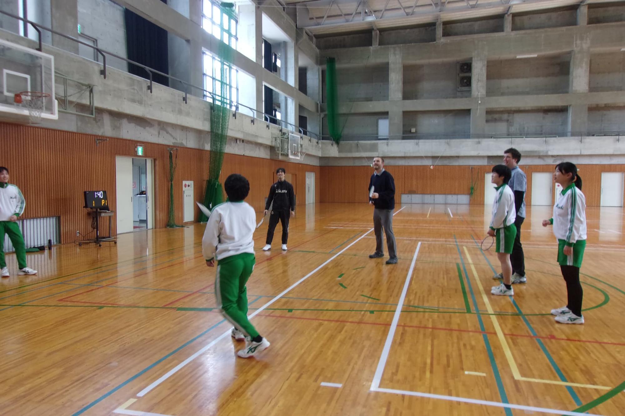 ALTの先生たちとバドミントンをする生徒たち