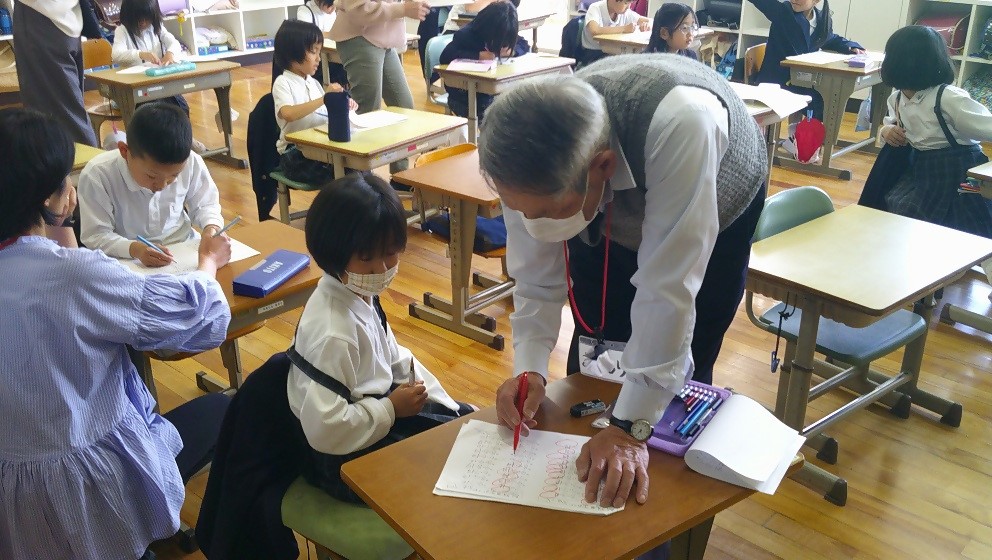 放課後、学習支援を受けている小学生の女の子と、女の子が見ているテキストを見ているボランティアの男性の写真